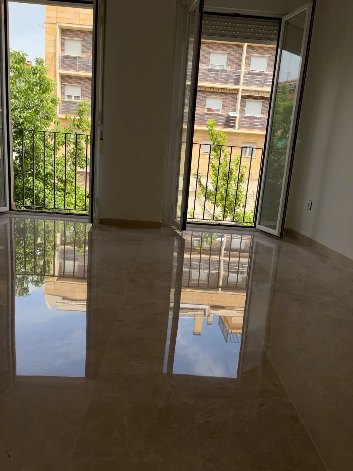 Suelo de mármol crema abrillantado con brillo espejo, reflejando la ventana de la estancia — trabajo real de Pulimentos Jiménez