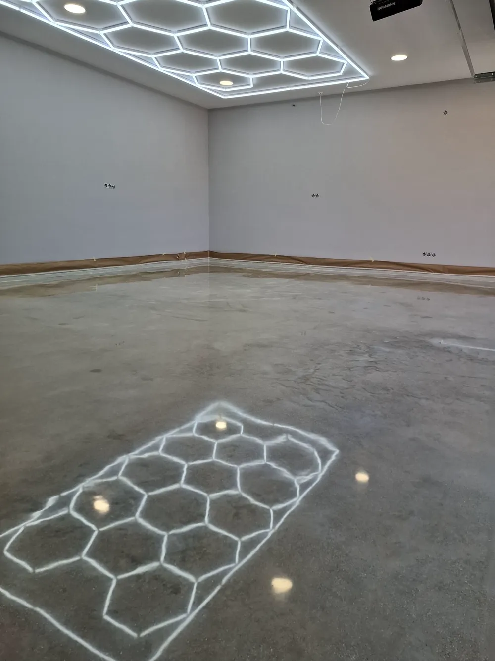 Garaje con suelo de hormigón pulido reflejando la iluminación hexagonal del techo — trabajo real de Pulimentos Jiménez